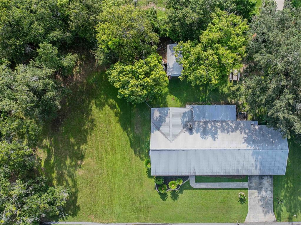 An aerial view shows a house with a metal roof, a driveway, and a large yard — 5934 RIDGE DRIVE, LAKELAND, FL