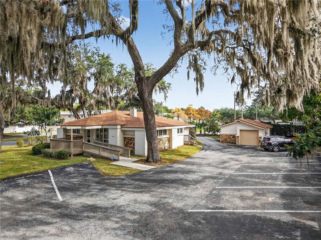 A single-story building with a wooden ramp and a detached garage under large trees — 708 LEE STREET, LEESBURG, FL