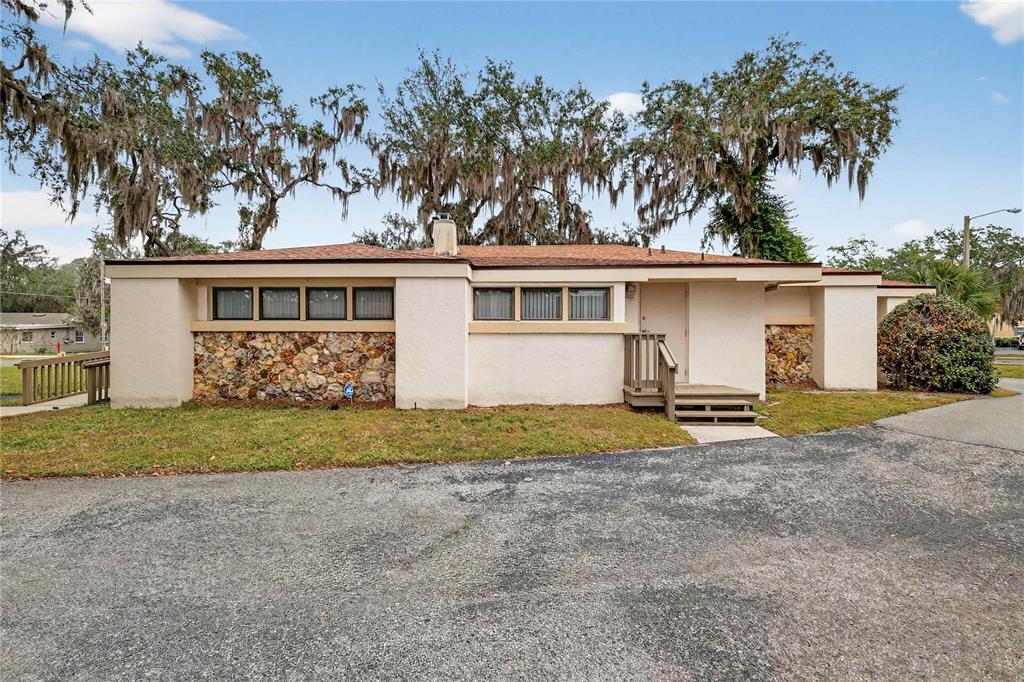 A single-story house with a stone facade, stucco walls, and a wooden entrance deck — 708 LEE STREET, LEESBURG, FL