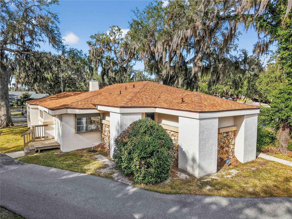 A single-story house with a tan shingled roof, stucco walls, and stone accents — 708 LEE STREET, LEESBURG, FL