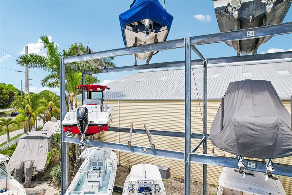 Boats are stored in a multi-level metal rack structure outdoors next to a building — 103950 OVERSEAS HIGHWAY UNIT RU62, KEY LARGO, FL