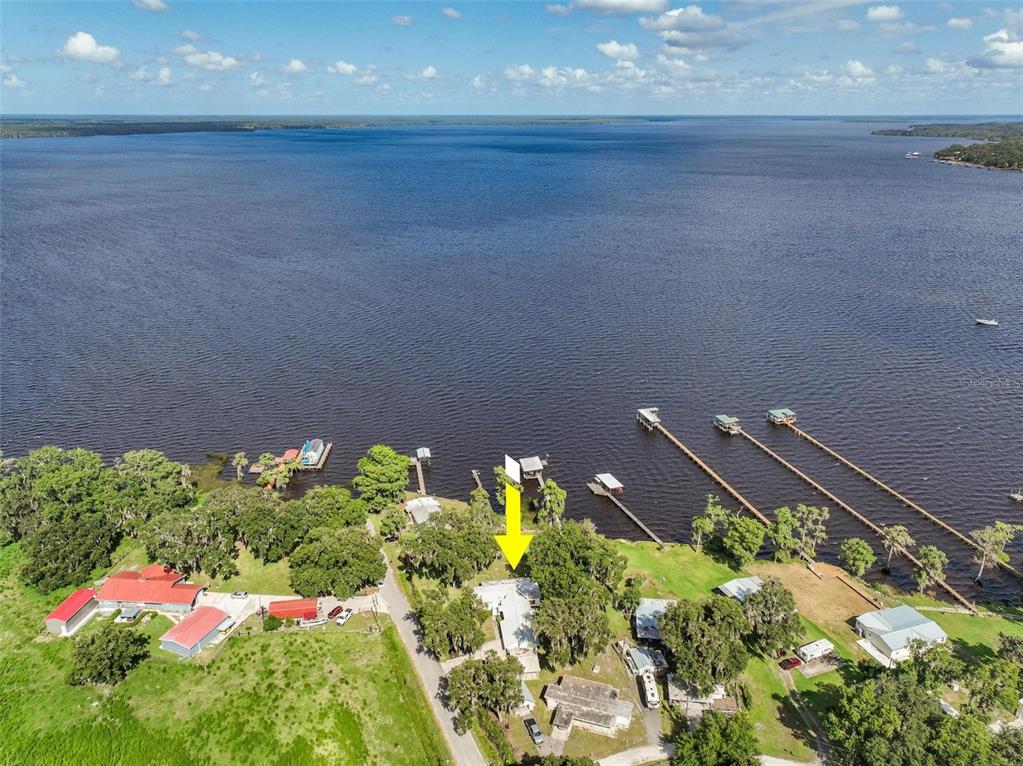 An aerial view shows a house with a yellow arrow pointing toward it near a lake — 311 POMONA LANDING ROAD, CRESCENT CITY, FL