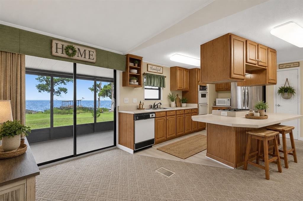 A kitchen with oak cabinets and a center island overlooks a lake through sliding doors — 311 POMONA LANDING ROAD, CRESCENT CITY, FL