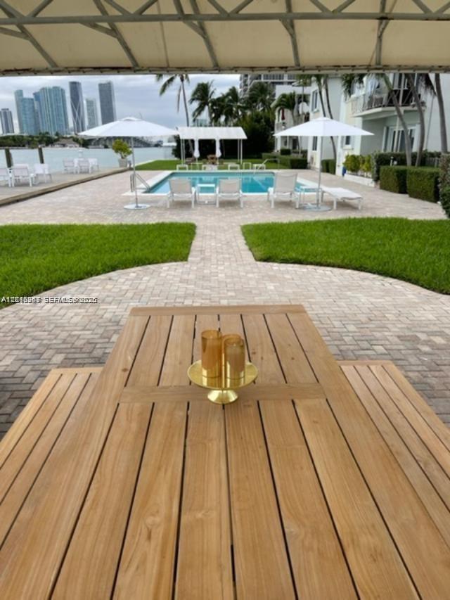 A wooden outdoor dining table overlooks a swimming pool, patio, and city skyline — 1140 Venetian Way # 2C, Miami FL 33139, MIAMI, FL