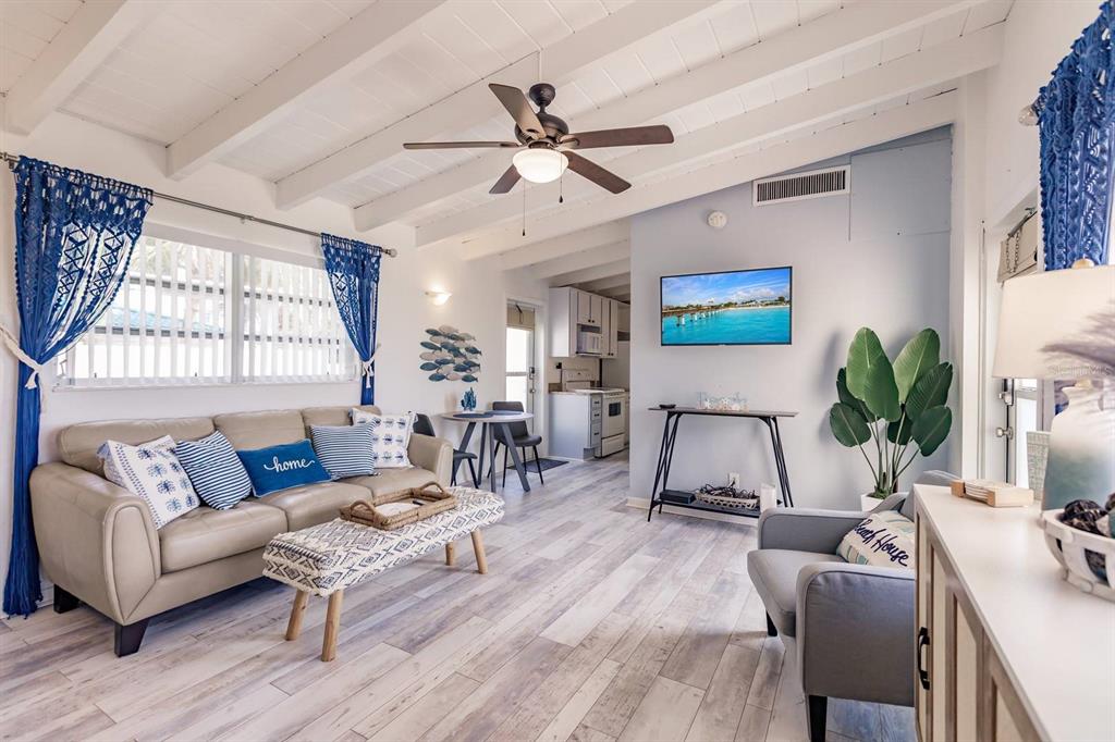 A living room features a beige sofa, a patterned ottoman, and a ceiling fan — 6006 MIDNIGHT PASS ROAD UNIT 10, SARASOTA, FL