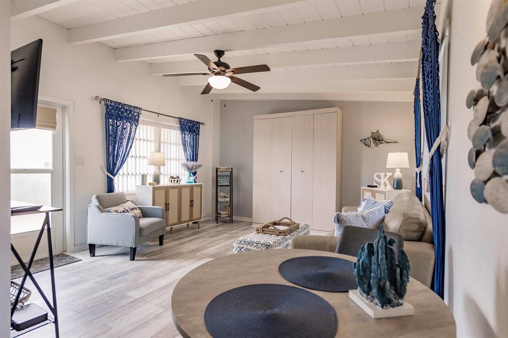 A living room with a ceiling fan, light wood flooring, and blue curtains — 6006 MIDNIGHT PASS ROAD UNIT 10, SARASOTA, FL