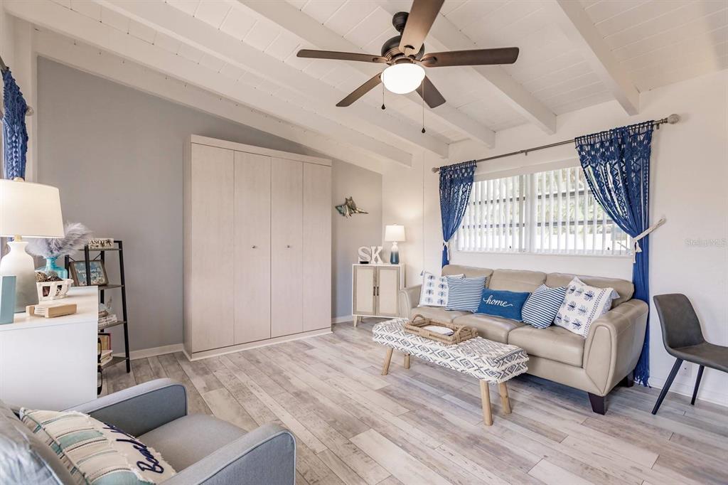 A living room features a vaulted ceiling, light wood flooring, a beige sofa, and cabinetry — 6006 MIDNIGHT PASS ROAD UNIT 10, SARASOTA, FL