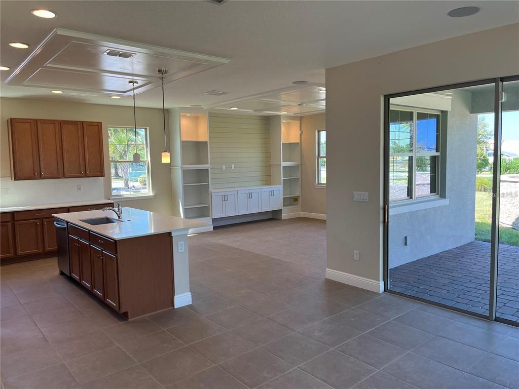 A kitchen with wood cabinets and an island opens into a living area with built-in shelving — 6673 KNOLLWOOD STREET, HARMONY, FL