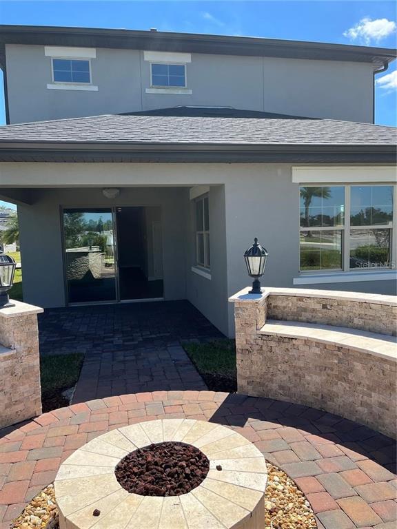 A backyard patio features a circular stone fire pit and a curved stone seating wall — 6673 KNOLLWOOD STREET, HARMONY, FL