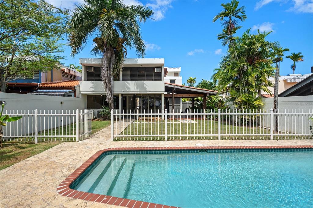 A swimming pool sits in front of a two-story house with a white fence — 2 CALLE 2 UNIT C5, SAN JUAN, PR