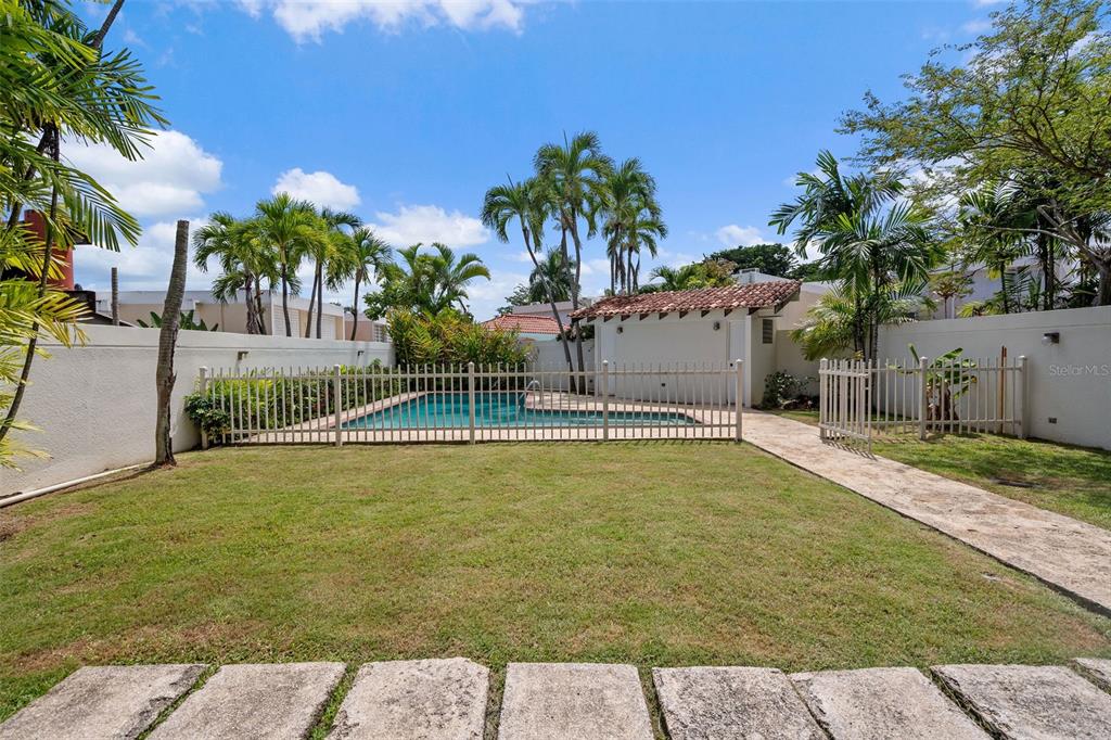 A fenced backyard features a swimming pool, palm trees, and a small structure with a roof — 2 CALLE 2 UNIT C5, SAN JUAN, PR