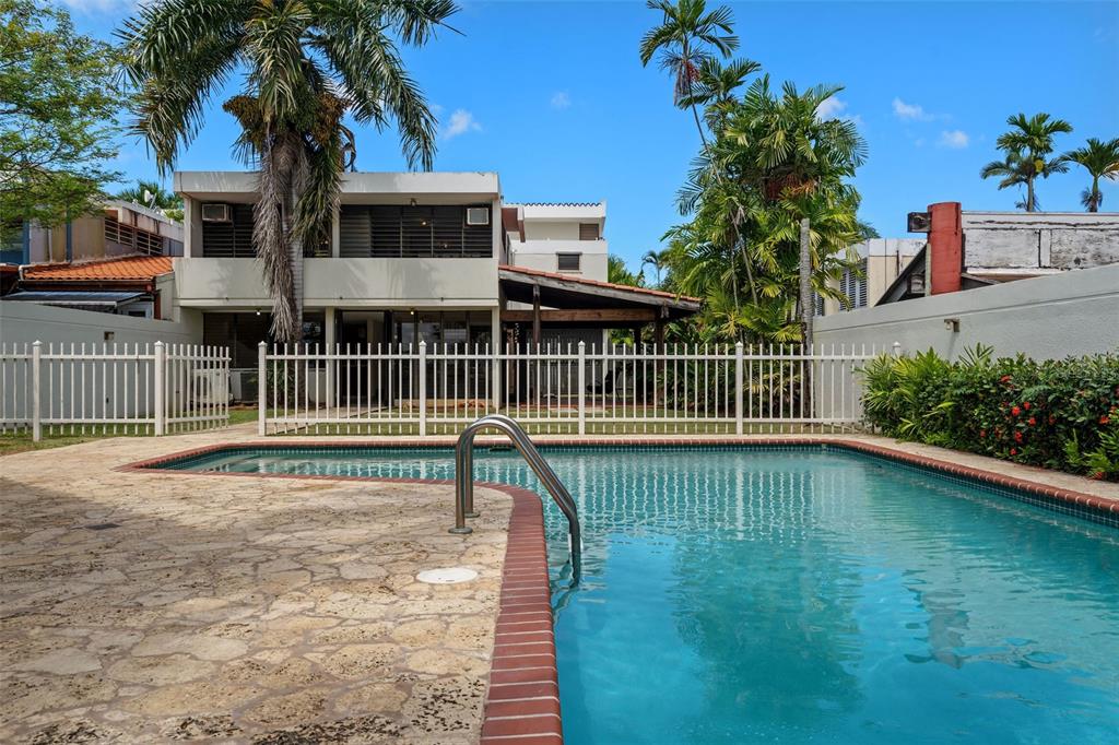 A swimming pool with a brick edge sits in front of a two-story house — 2 CALLE 2 UNIT C5, SAN JUAN, PR