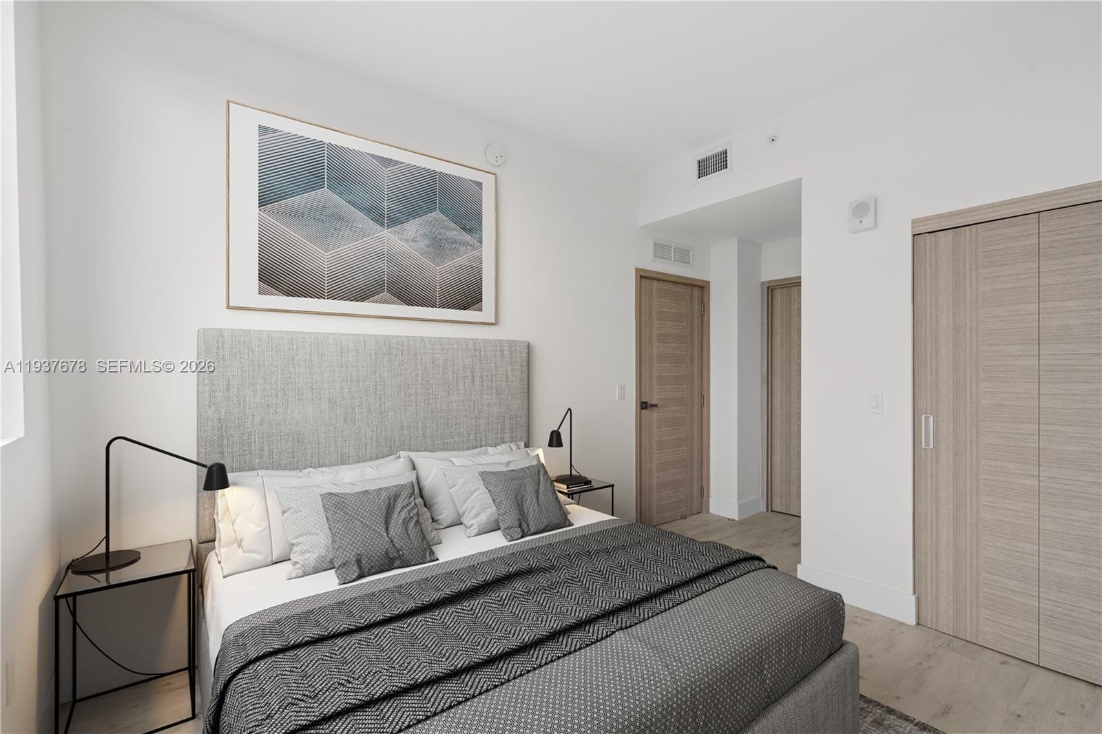 A modern bedroom features a gray upholstered headboard, two bedside lamps, and light wood doors — 1601 SW 32 Avenue # 514, Miami FL 33145, MIAMI, FL