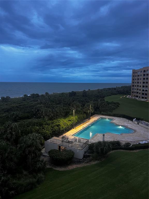 An elevated view shows a swimming pool, lush greenery, and the ocean at dusk — 104 A SURFVIEW DRIVE UNIT 2503, PALM COAST, FL