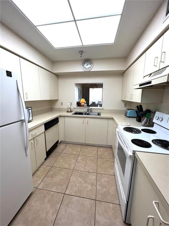 A kitchen features white cabinets, tile flooring, a drop-in sink, and a large skylight — 104 A SURFVIEW DRIVE UNIT 2503, PALM COAST, FL