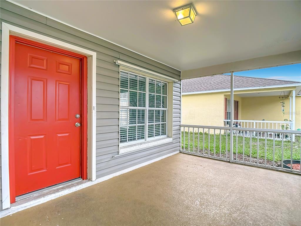A covered porch with a red front door, gray siding, and a screened-in railing — 7834 CHADWICK DRIVE, NEW PORT RICHEY, FL