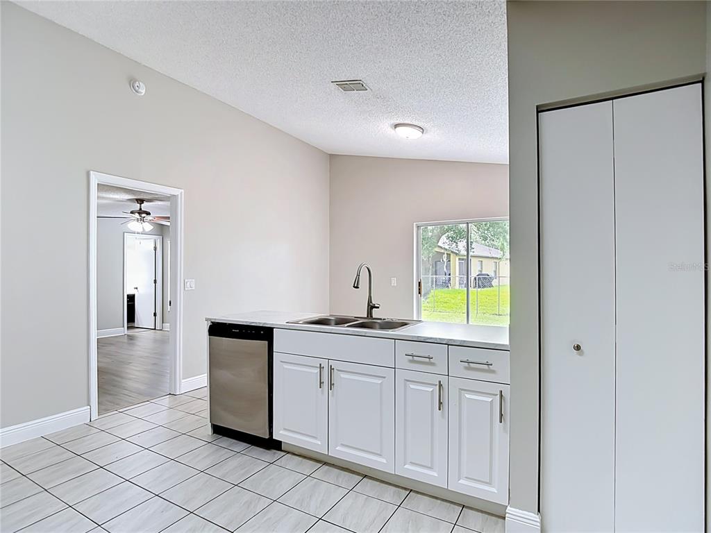 A kitchen features white cabinets, a stainless steel dishwasher, and a double-basin sink — 7834 CHADWICK DRIVE, NEW PORT RICHEY, FL