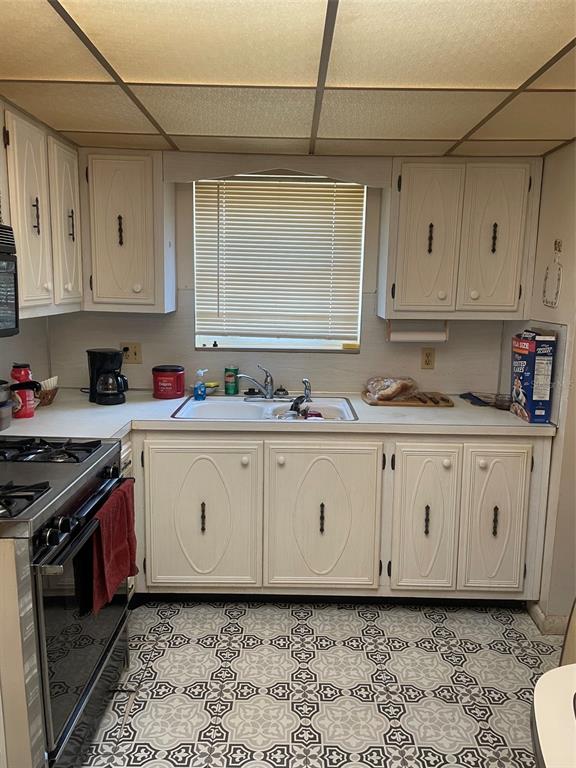 A kitchen features white cabinets, a double sink, a gas range, and patterned floor tiles — 5287 81ST STREET N UNIT 12, ST PETERSBURG, FL