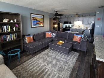 A living room features a gray sectional sofa, a patterned rug, and an open kitchen — 4363 TAHITIAN GARDENS CIRCLE UNIT G, HOLIDAY, FL