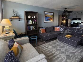 A living room features a grey sectional sofa, a bookshelf, and a table lamp — 4363 TAHITIAN GARDENS CIRCLE UNIT G, HOLIDAY, FL