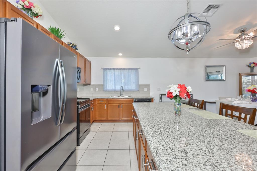 A kitchen features wood cabinets, granite countertops, stainless steel appliances, and a large center island — 7640 MUSCOVY DRIVE, LAKELAND, FL