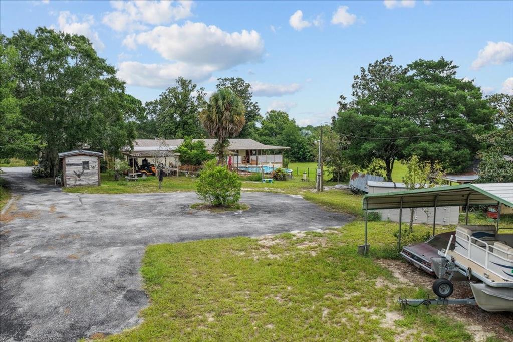 A gravel driveway leads to a house with a pool, shed, and covered boat storage — 470 FAY AVENUE, SPRING HILL, FL