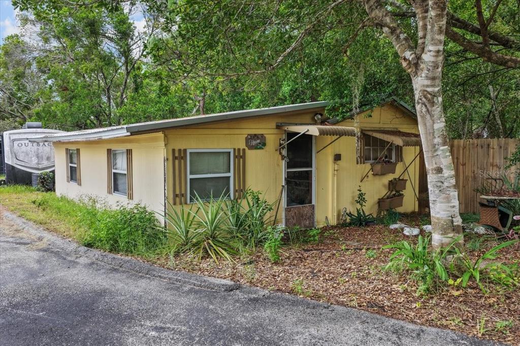 A yellow single-story mobile home sits next to a parked camper under mature trees — 470 FAY AVENUE, SPRING HILL, FL
