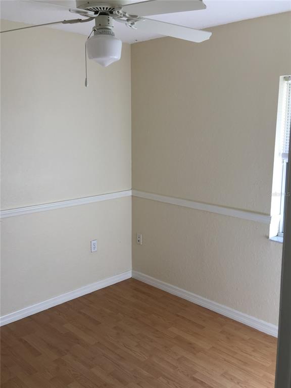 An empty room features light-colored walls with chair rail molding, wood-look flooring, and a ceiling fan — 2417 GOLFVIEW STREET, LAKELAND, FL