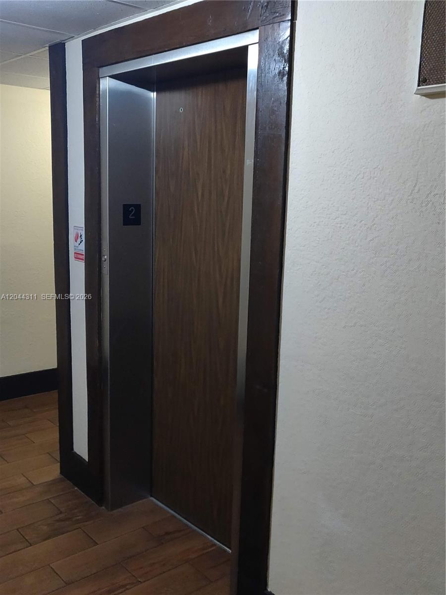 An elevator door with a wood-look finish is framed by dark wood trim — 3750 Inverrary Dr # 2Q, Lauderhill FL 33319, LAUDERHILL, FL