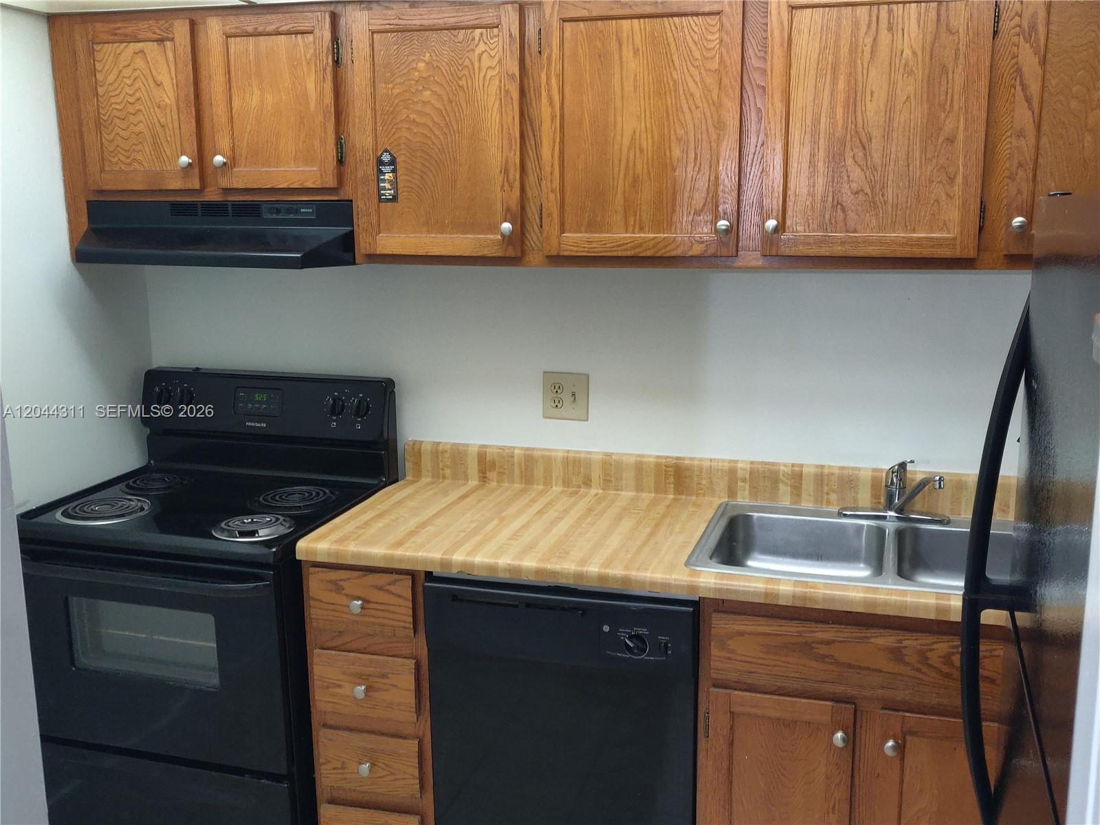 A kitchen features wood cabinets, a black stove, a dishwasher, and a laminate countertop — 3750 Inverrary Dr # 2Q, Lauderhill FL 33319, LAUDERHILL, FL