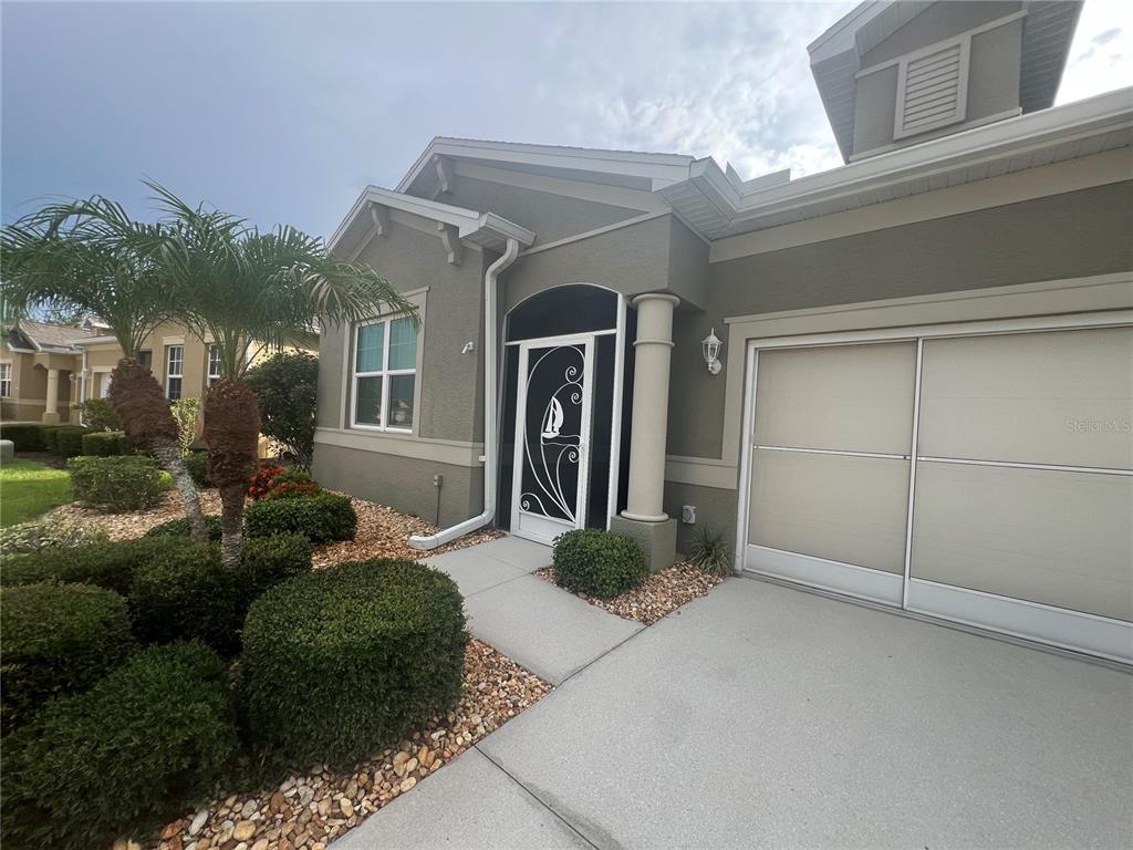 A single-story house exterior features a beige stucco facade, a garage, and a screened entryway — 1829 KNIGHTS BRIDGE TRAIL, PORT CHARLOTTE, FL