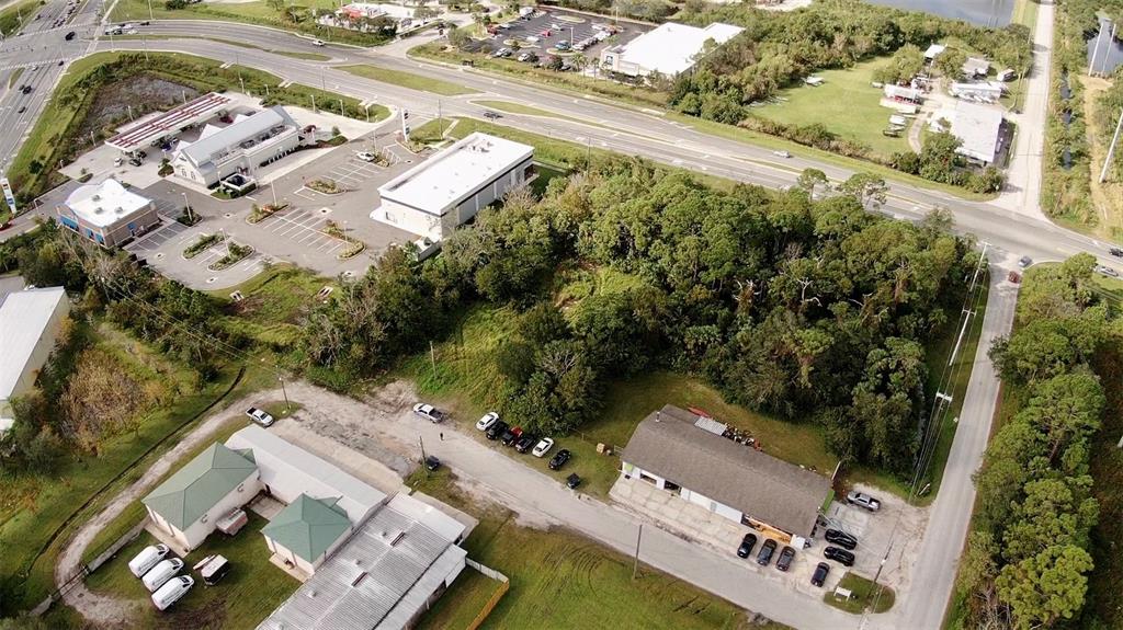 Aerial view of commercial buildings, parking lots, and wooded areas near a road intersection — 4640 CALLE CORTO, TITUSVILLE, FL