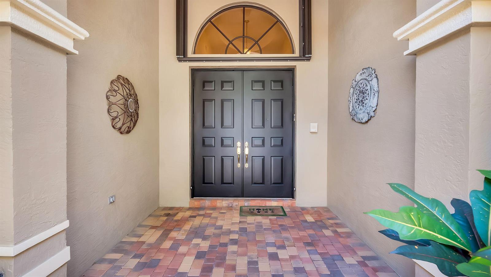 A front entryway features double black doors, a semi-circular transom window, and paver flooring — 11012 Vía Sorrento, Boynton Beach FL 33437, BOYNTON BEACH, FL
