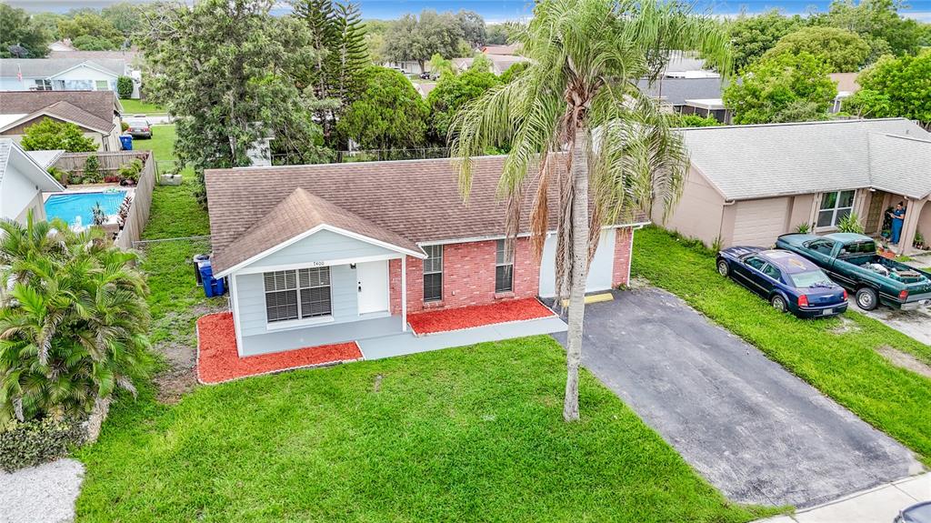 An aerial view shows a single-story house with a brick and light blue exterior — 7400 MITCHELL RANCH ROAD, NEW PORT RICHEY, FL