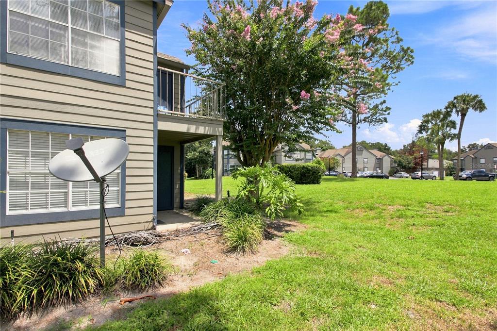 A view of a tan apartment building exterior with a balcony, satellite dish, and landscaping — 939 FRAMLINGHAM COURT UNIT 103, LAKE MARY, FL