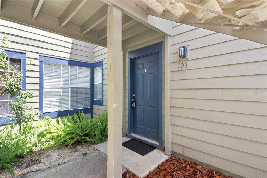 The exterior entrance of a residential unit features a blue door labeled 103 — 939 FRAMLINGHAM COURT UNIT 103, LAKE MARY, FL