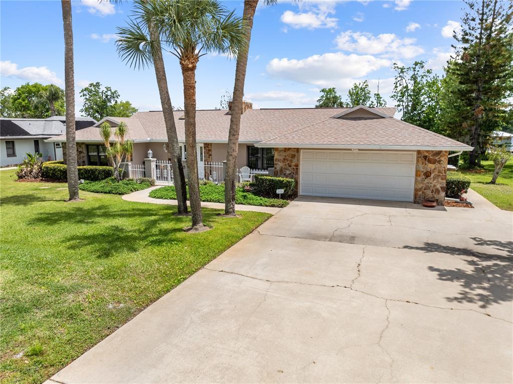 A single-story house with a stone facade, a two-car garage, and palm trees in front — 6770 BAY SHORE DRIVE, ST CLOUD, FL