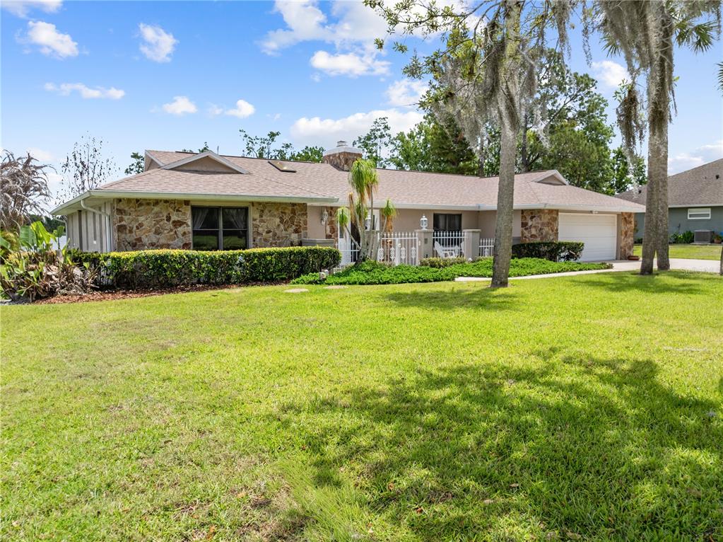 A single-story house with a stone facade, a two-car garage, and a large front lawn — 6770 BAY SHORE DRIVE, ST CLOUD, FL