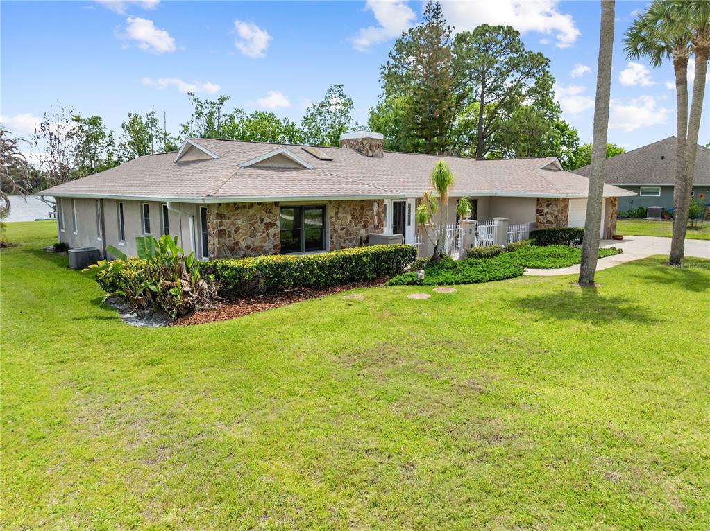 A single-story house with a stone facade, a shingled roof, and a large front lawn — 6770 BAY SHORE DRIVE, ST CLOUD, FL