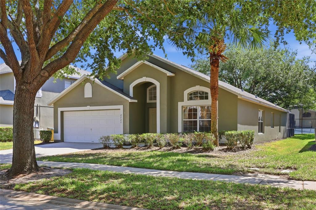 A single-story house with a two-car garage, arched entryway, and a palm tree in front — 2721 LIDO KEY DRIVE, KISSIMMEE, FL