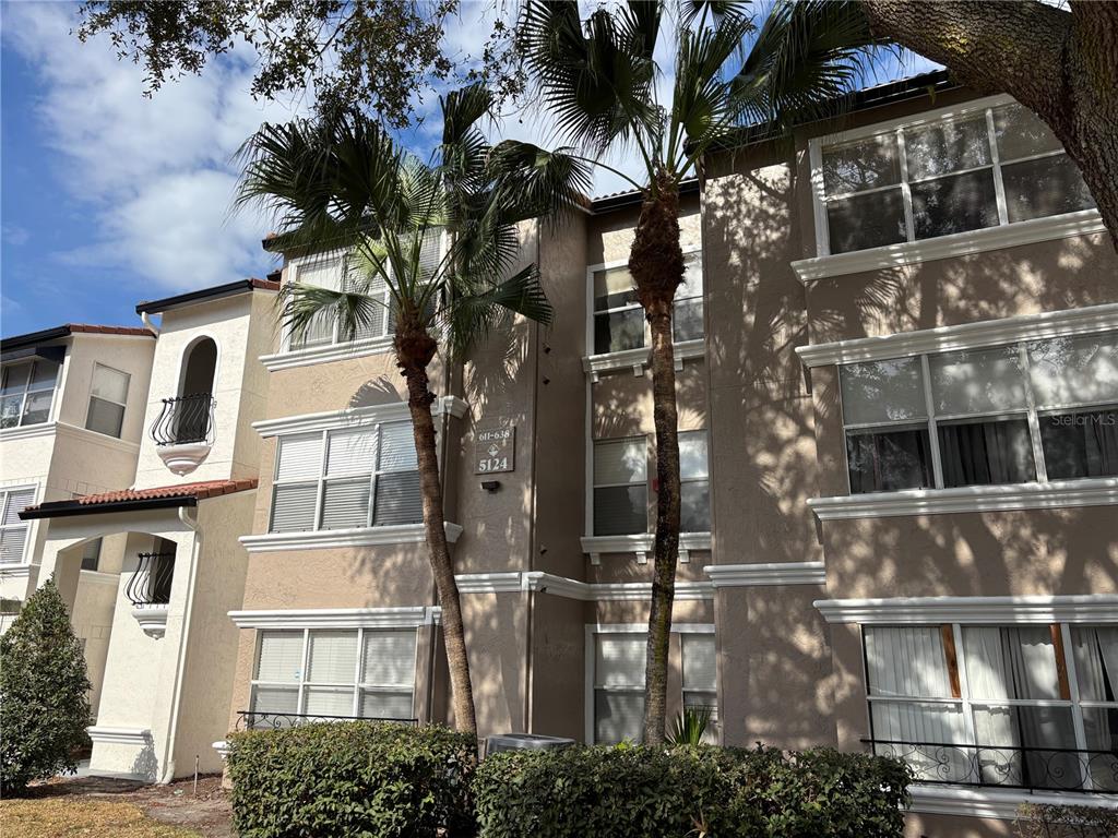 A three-story tan apartment building exterior features palm trees and a small balcony — 5124 CONROY ROAD UNIT 623, ORLANDO, FL
