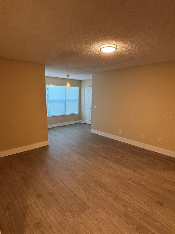An empty room with light-colored walls, wood-look flooring, and a white door in the background — 5124 CONROY ROAD UNIT 623, ORLANDO, FL