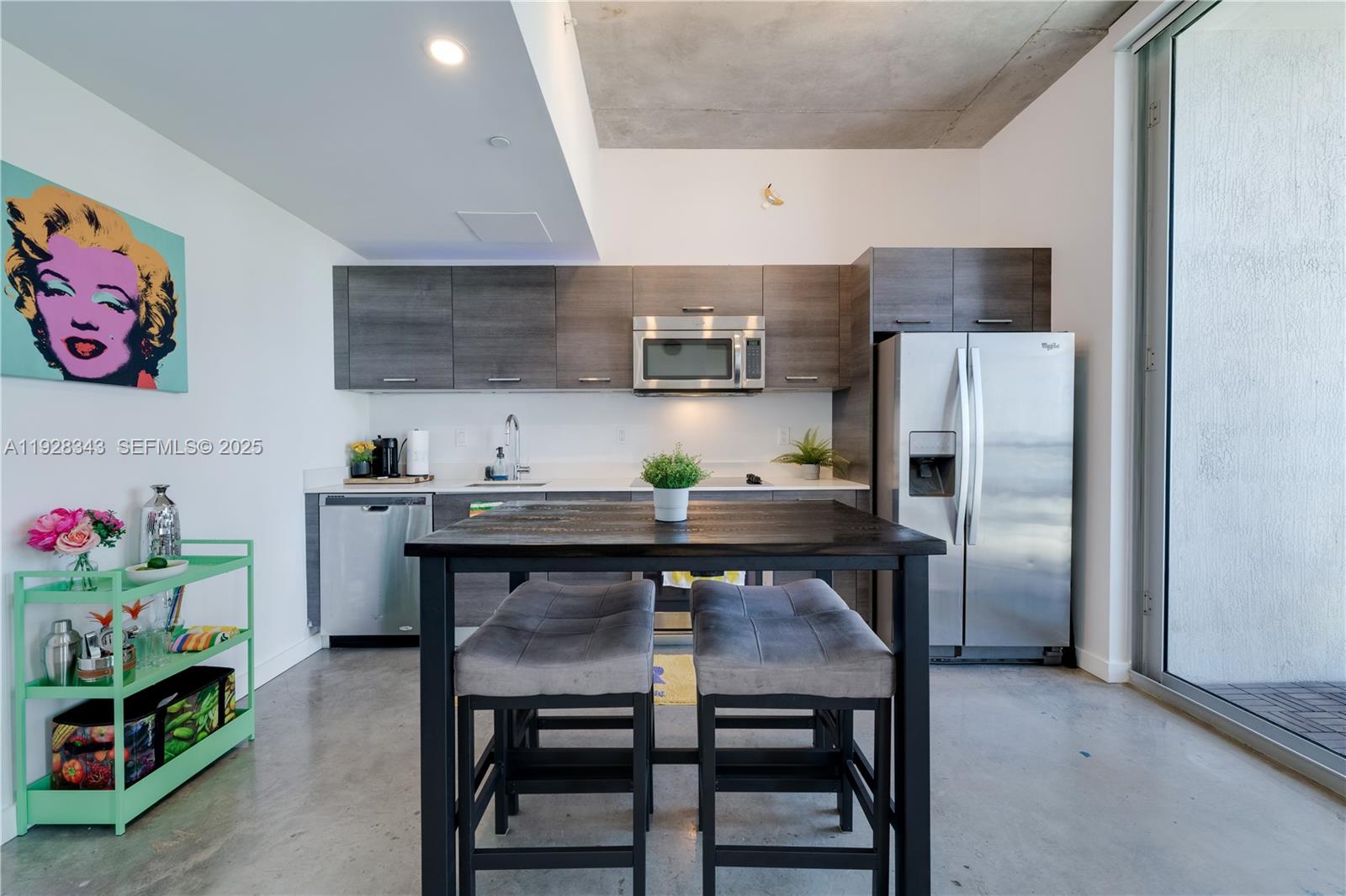 A modern kitchen features dark wood cabinets, stainless steel appliances, and a central dining table — 151 SE 1st St # 3008, Miami FL 33131, MIAMI, FL