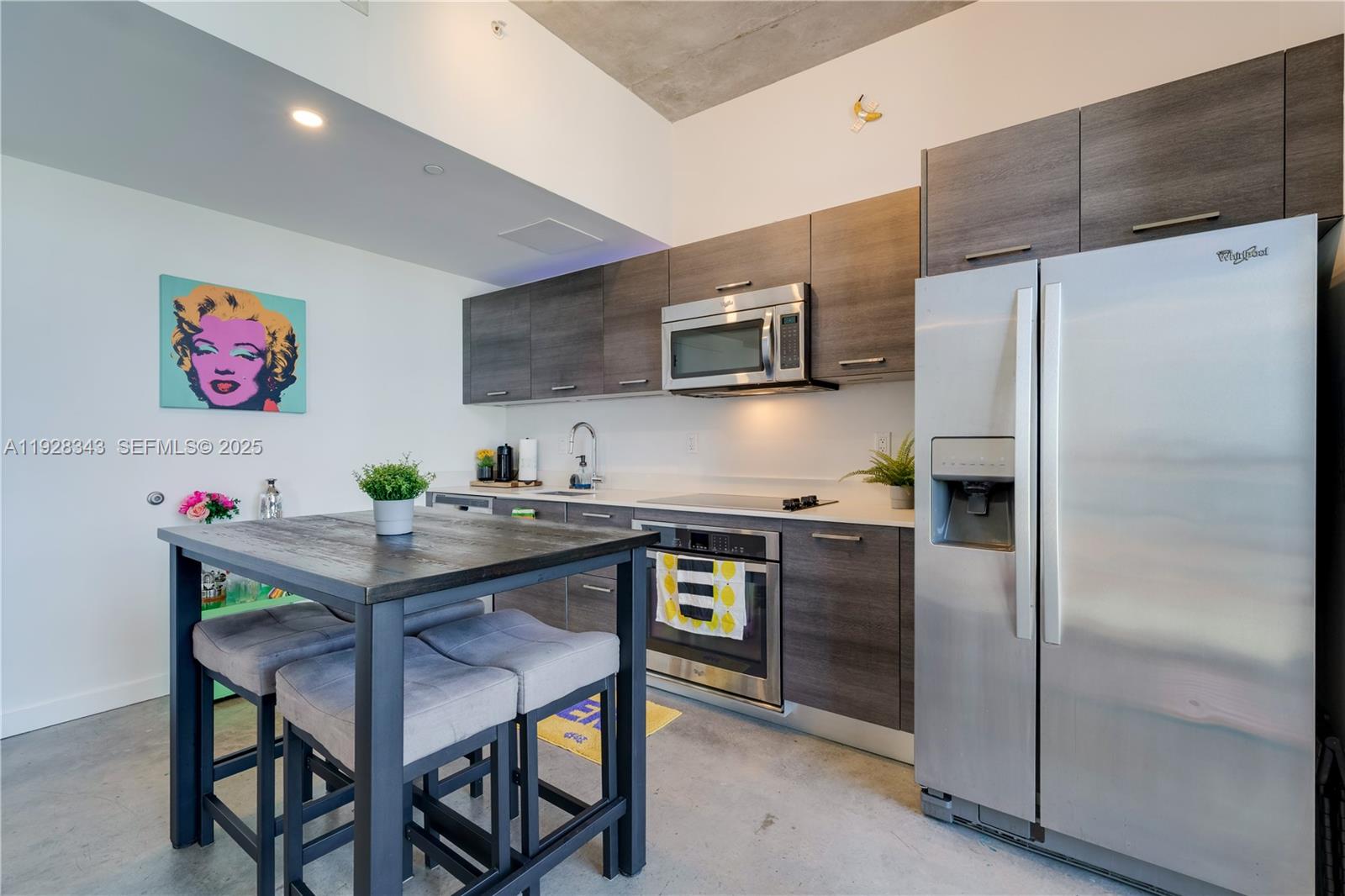 A modern kitchen features dark wood cabinetry, stainless steel appliances, and a central dining table — 151 SE 1st St # 3008, Miami FL 33131, MIAMI, FL