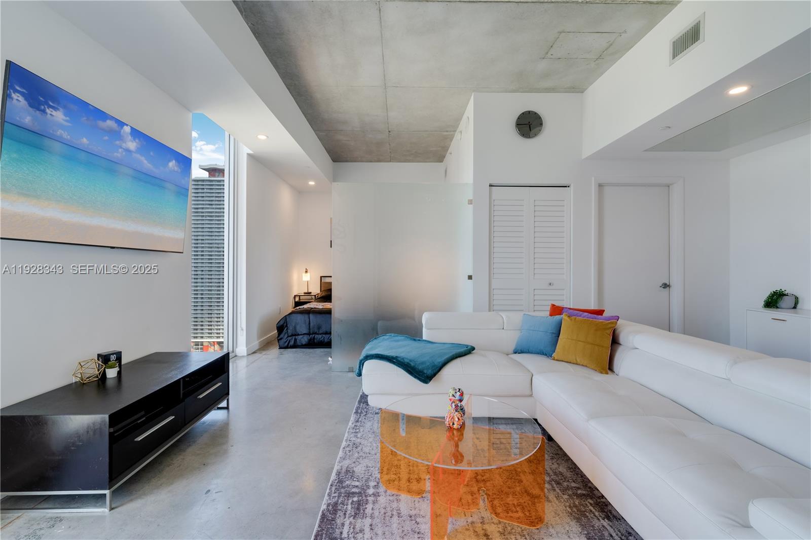 A modern living room features a white sectional sofa, concrete ceiling, and a glass partition — 151 SE 1st St # 3008, Miami FL 33131, MIAMI, FL