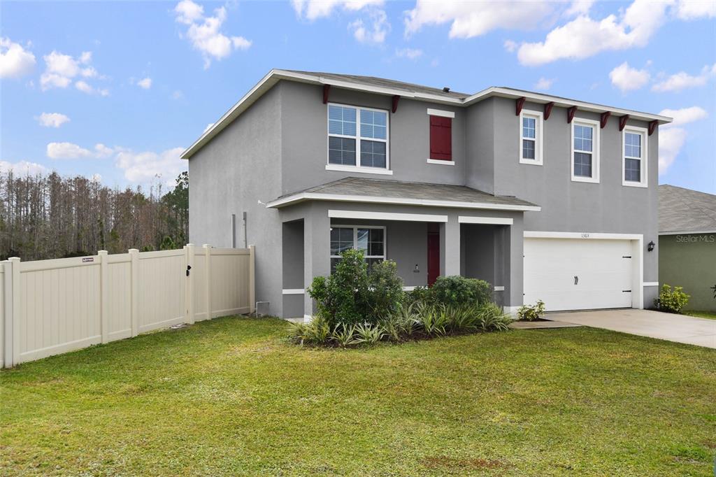 A two-story gray house with a white garage door and a vinyl privacy fence — 1363 FOX SQUIRREL DRIVE, DAVENPORT, FL