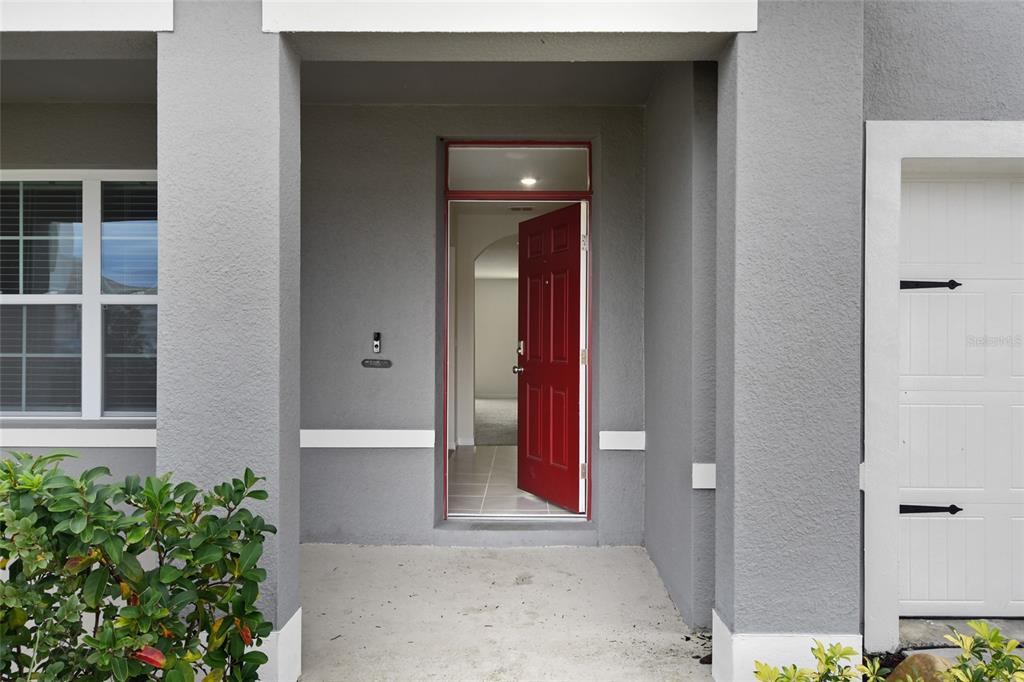 A red front door stands open to a home entrance with a gray exterior — 1363 FOX SQUIRREL DRIVE, DAVENPORT, FL