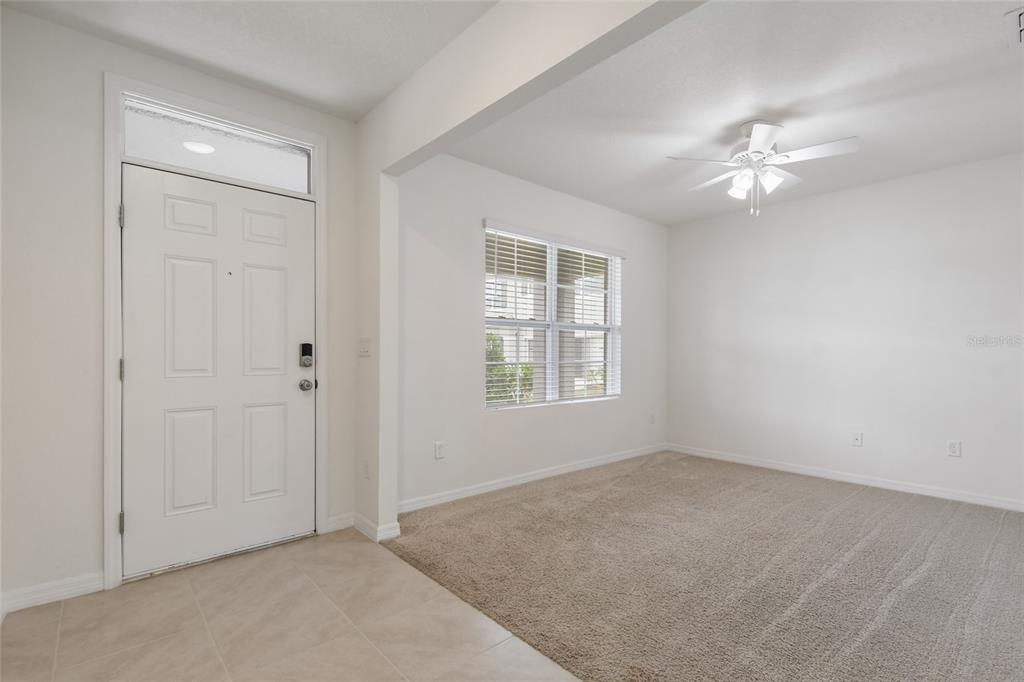 An entryway with tile flooring leads into a carpeted living area with a ceiling fan — 1363 FOX SQUIRREL DRIVE, DAVENPORT, FL