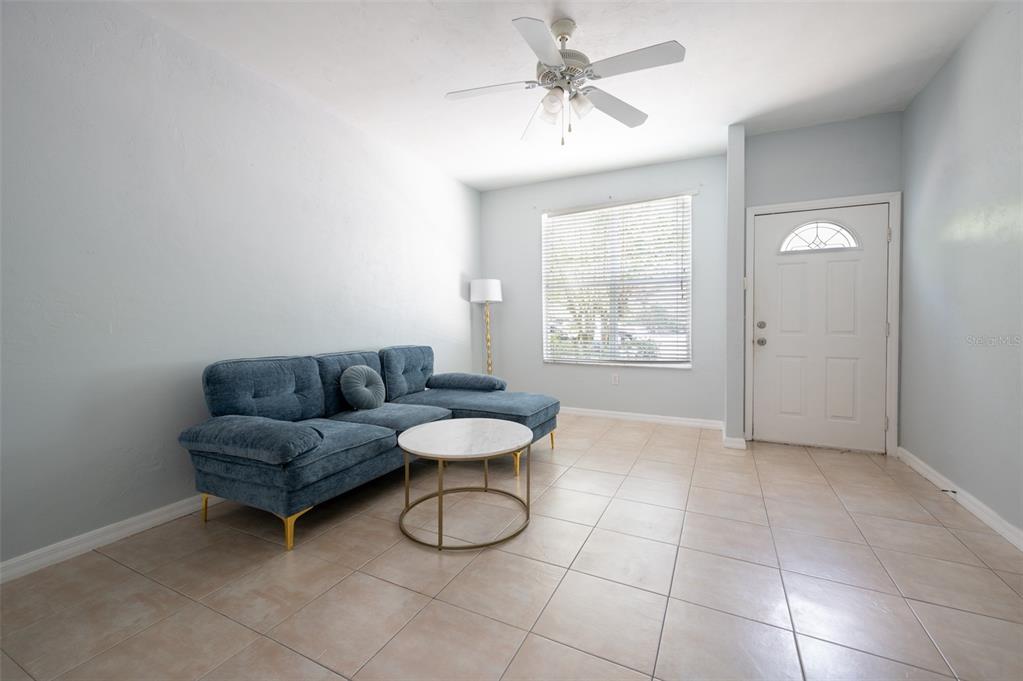 A living room features a blue sectional sofa, a round coffee table, and tile flooring — 3860 SW 20TH AVENUE UNIT 1808, GAINESVILLE, FL