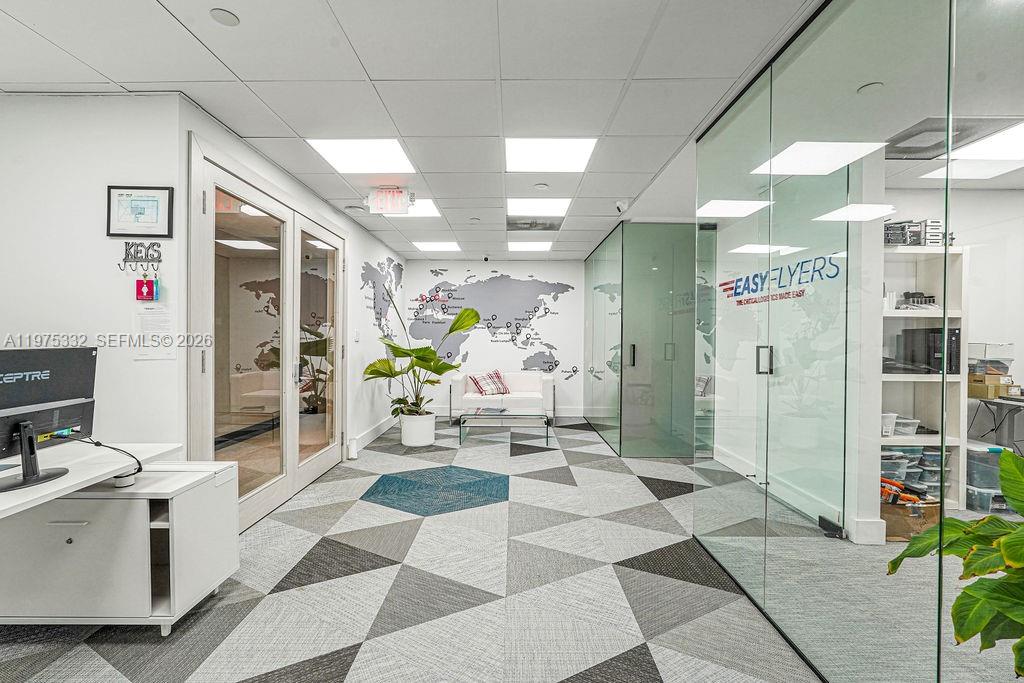 An office interior features a geometric patterned carpet, a world map wall mural, and glass partitions — 1110 Brickell Ave # 700A, Miami FL 33131, MIAMI, FL